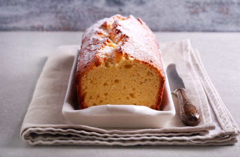 A cloth with a white dish with a cream cheese pound cake