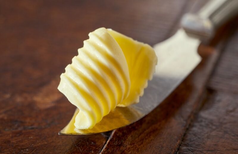 A knife with a curl of butter on a wooden table