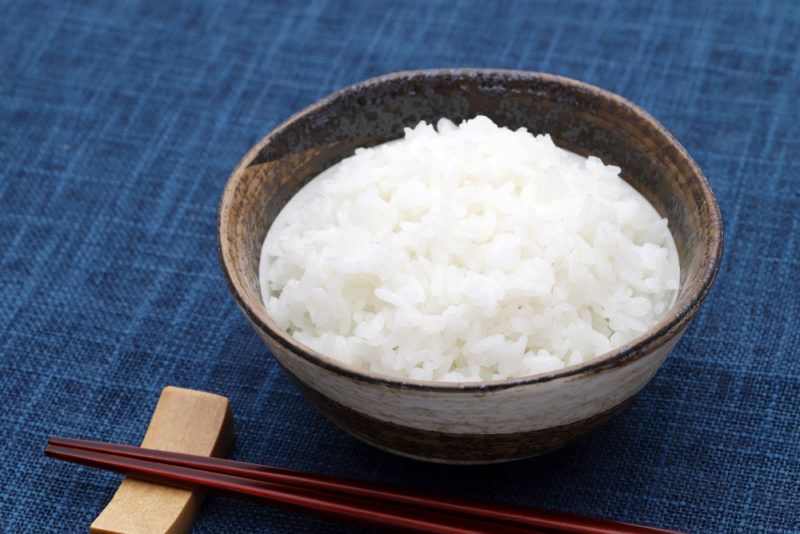 A dark bowl of cooked rice on a blue background