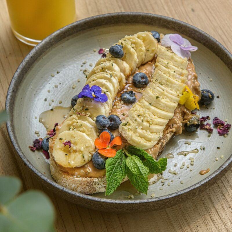 A gray plate with a piece of sourdough, sliced bananas, and nut butter