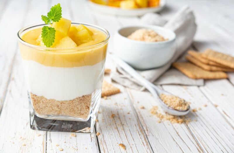 A glass jar with a dessert made using graham crackers, yogurt, and fruit