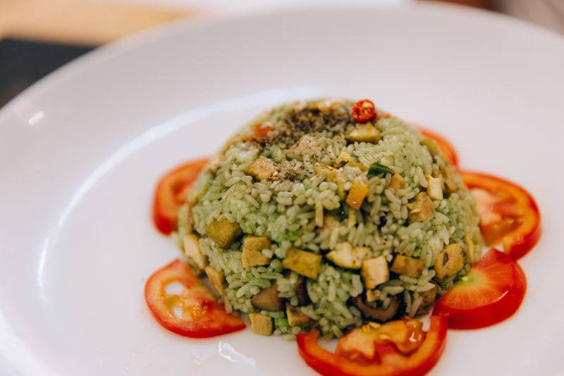 A white plate with a dish of com rang on top of sliced tomatoes