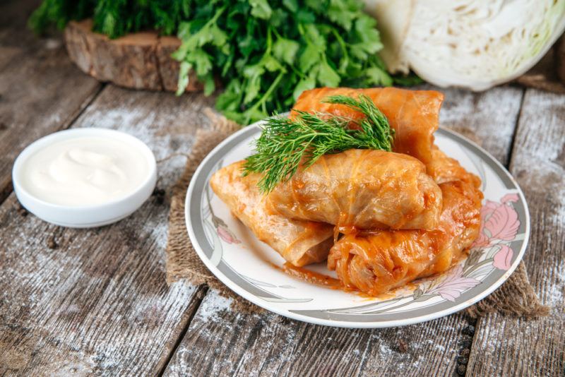 A small plate of golubtsy next to a white dish of sauce