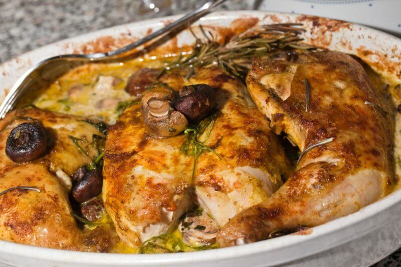 A white dish containing roast Provençal chicken