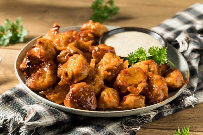 A dish of vegan chicken wings with sauce on a black and white towel