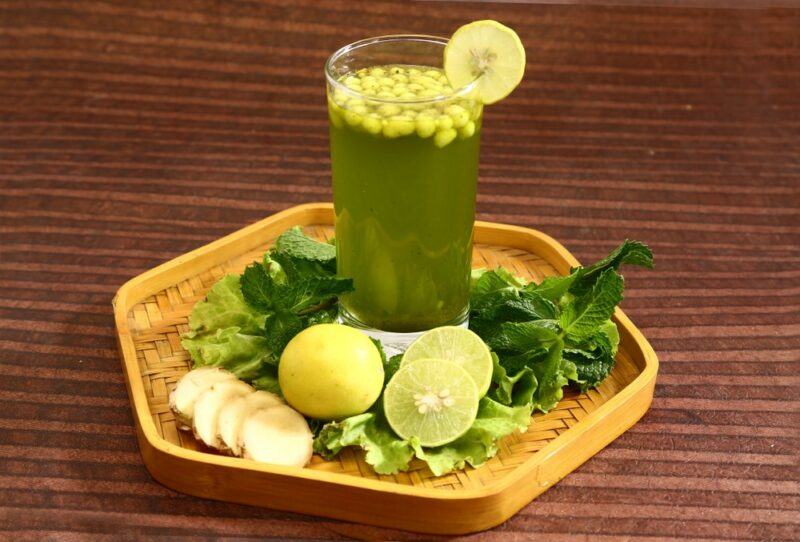 A wooden hexagon dish with ingredients and a glass of jal jeera