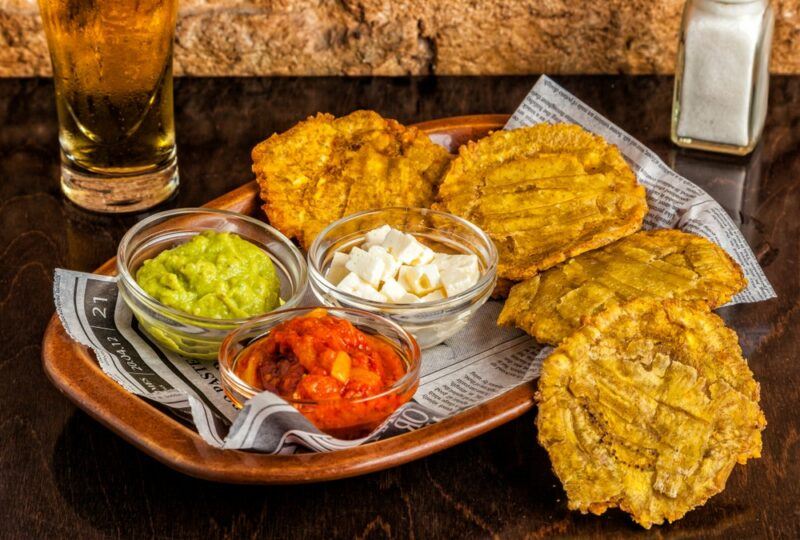 A black dish with tostones and three types of dish