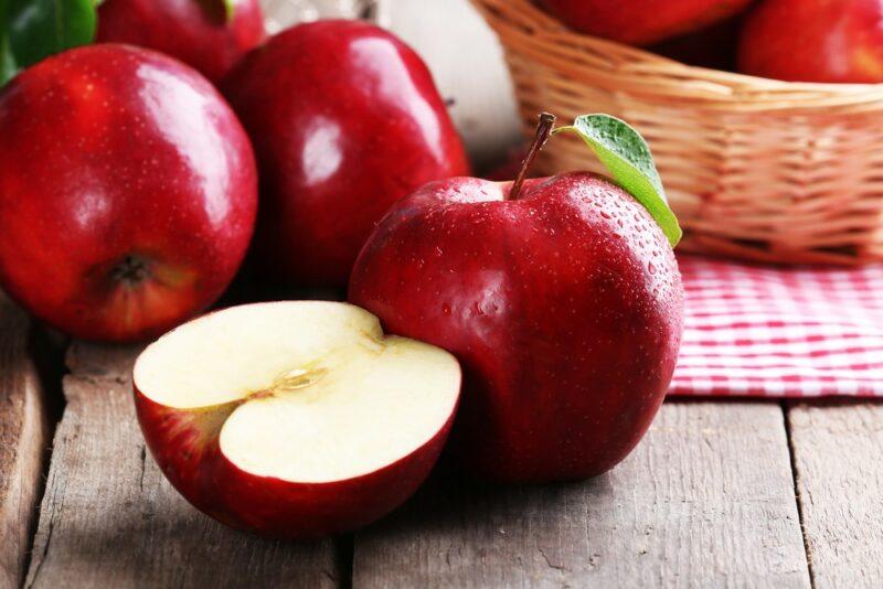 A few fresh red apples, one of which has been cut in half