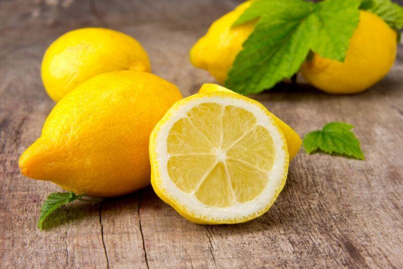 A wooden table with whole lemons and a lemon half