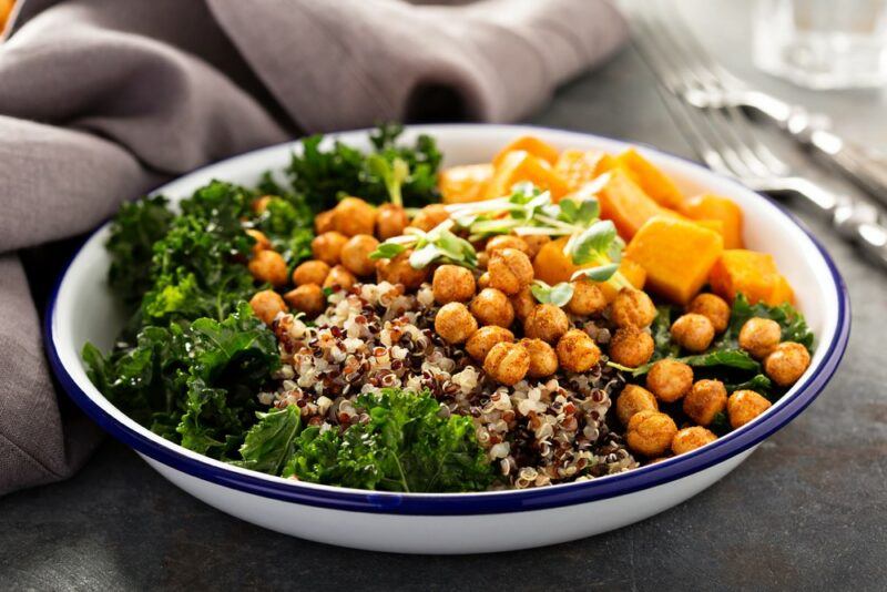 A large blue and white dish containing a quinoa and chickpea salad with greens