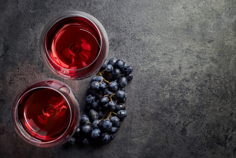 Two glasses of pinot noir and grapes on a gray table