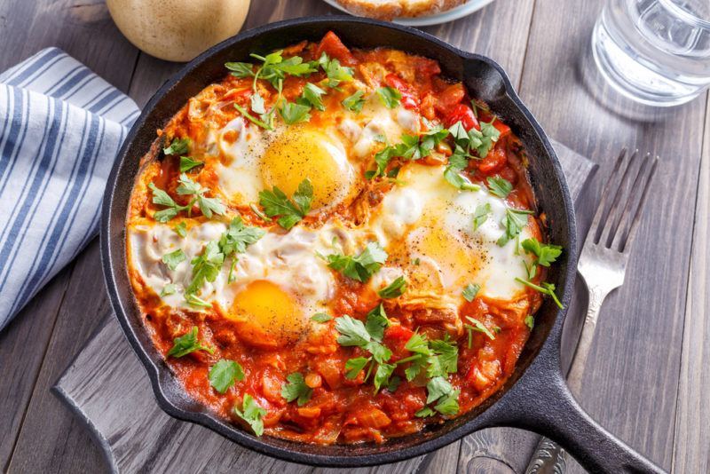 A cast iron fry pan with eggs and sauce