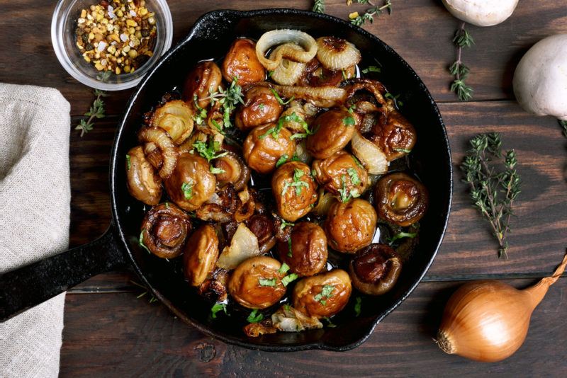 A black cast iron frypan containing cooked mushrooms