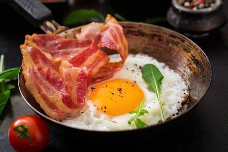 A small frypan with an egg and some bacon