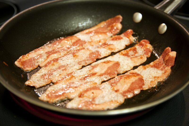 A frypan with turkey bacon being cooked