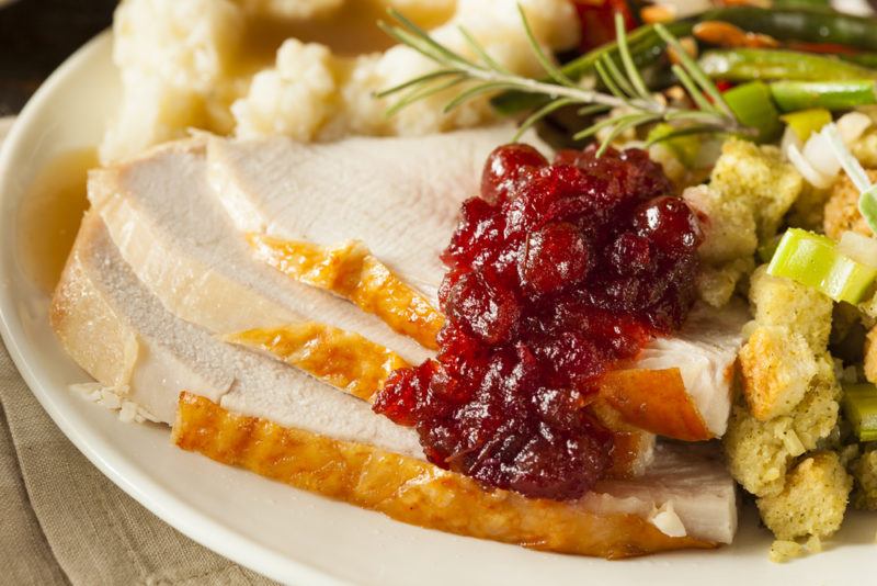 A white plate with a full turkey dinner, including stuffing, cranberry sauce, potatoes, and the turkey