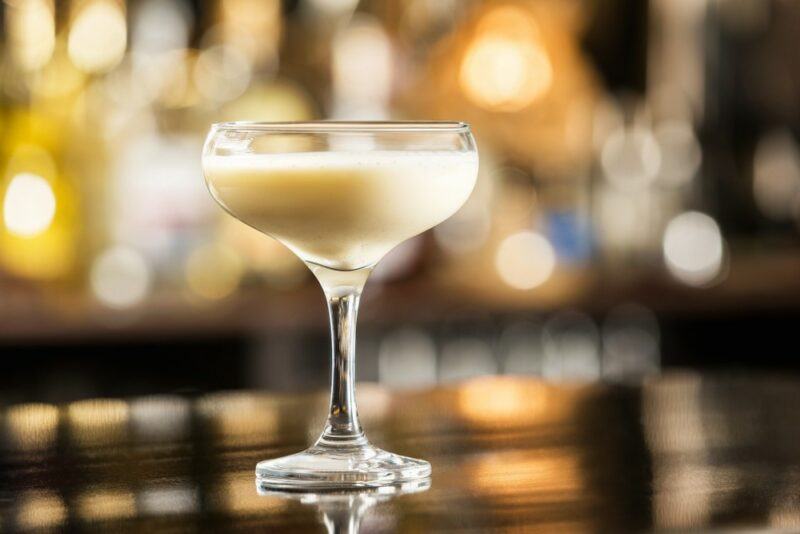 A coupe glass on a bar, containing a giant's milk cocktail