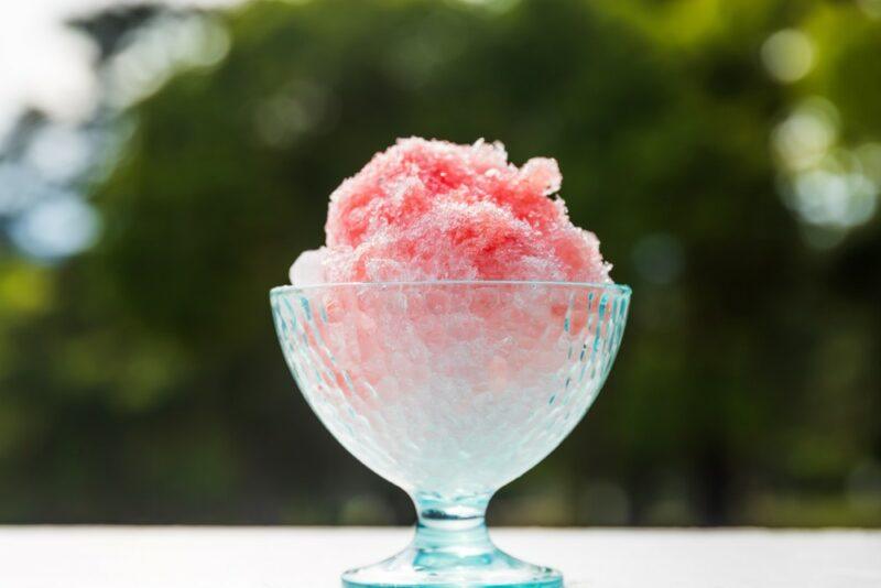 A glass bowl with a red mai tai snow cone or dessert