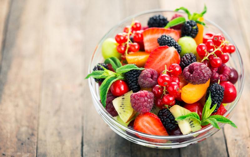 A white bowl with many types of fresh fruit