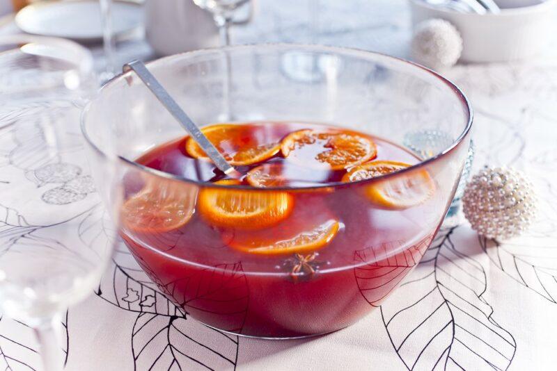 A bowl of Christmas punch with oranges on a table