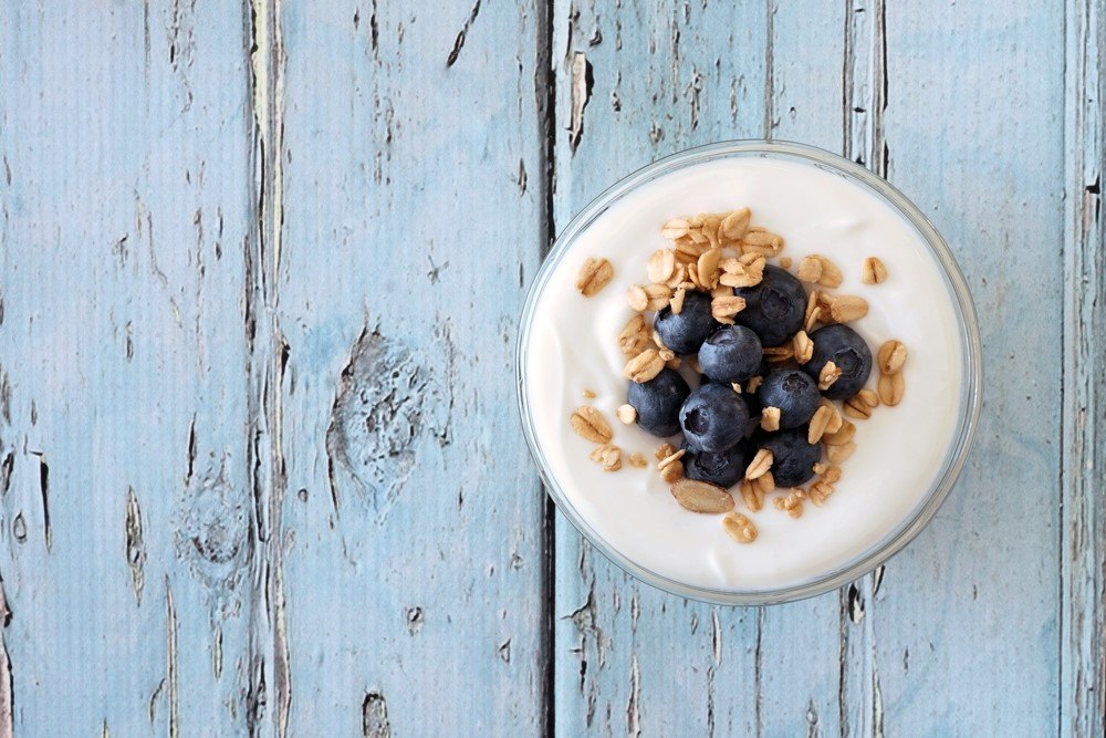 A glass jar with yogurt, oatmeal, and blueberries