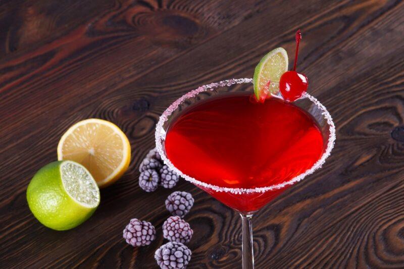 A bright red Bacardi cocktail in a martini glass, next to fruit