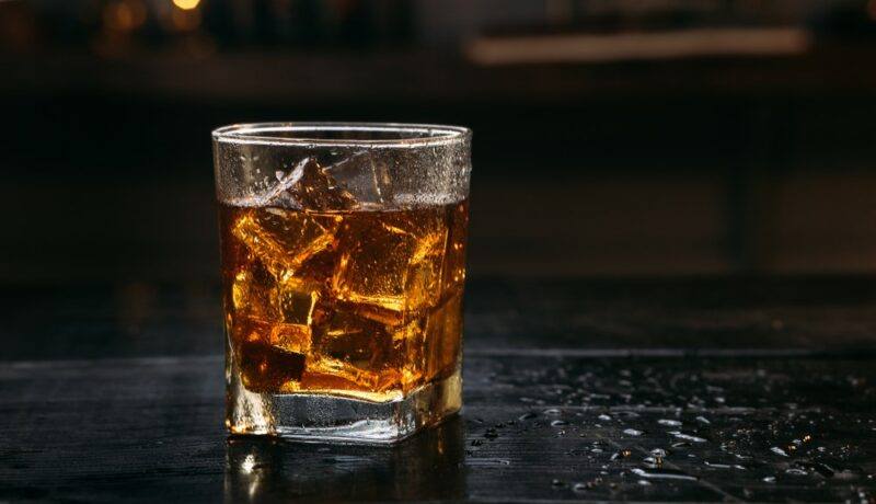 A glass of Angry Bee cocktail with nice on a bar against a dark background