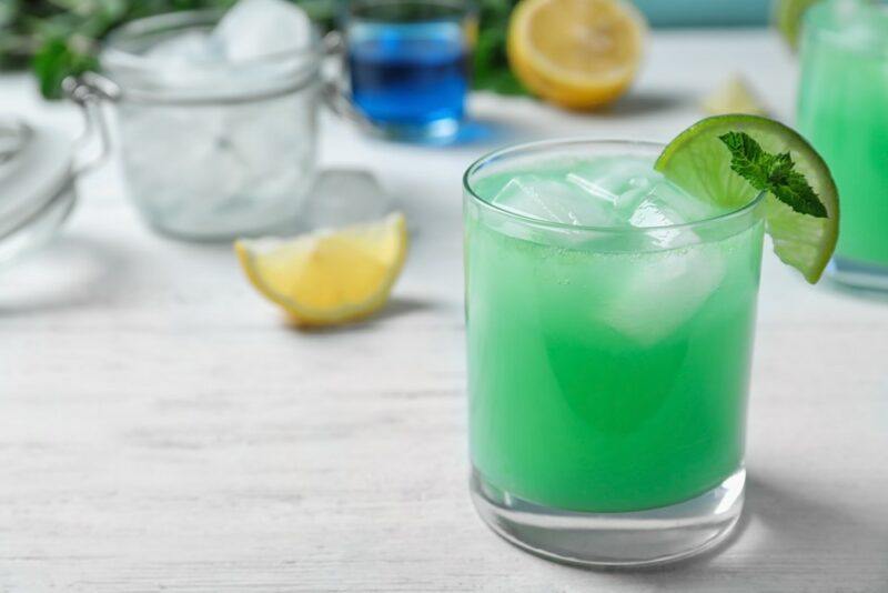 A glass containing a green cocktail or loaded tea on a table outside