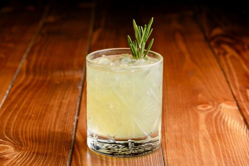 A glass containing a key lime moonshine cocktail on its own on a wooden table