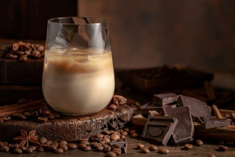 A glass containing a wake up call cocktail, surrounded by chocolate and coffee beans