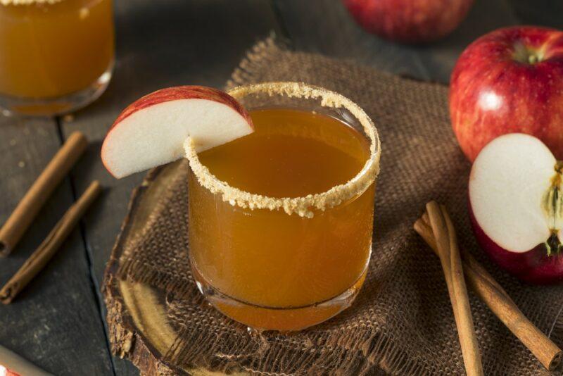 A single glass containing an apple pie moonshine cocktail rimmed with brown sugar or cinnamon