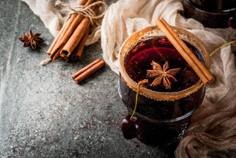 A glass containing hot rum punch with cinnamon sticks