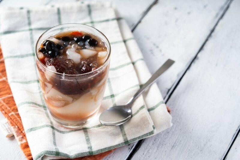 A cloth with a glass containing a taho tofu dessert, next to a spoon