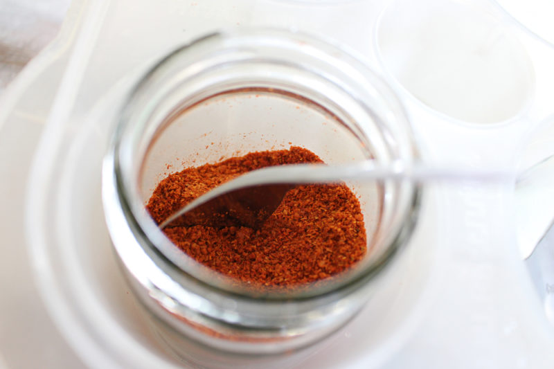 A small glass jar containng cayenne pepper and a spoon