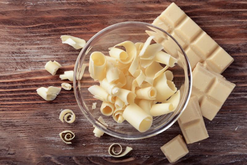 A wooden table with blocks of white chocolate and a bowl of white chocolate shavings