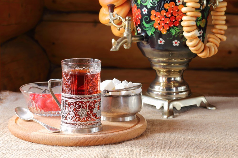 A glass mug of Russian tea next to sugar and flowers