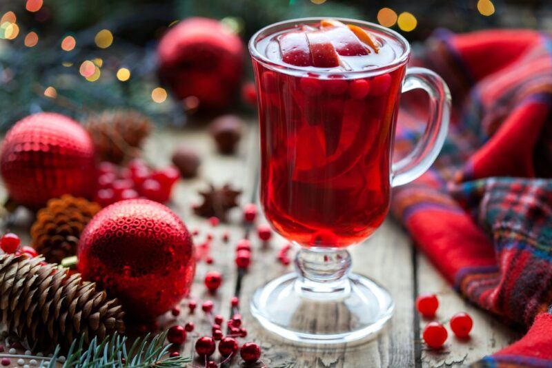 A glass mug filled with cranberry punch with cranberries, next to Christmas baubles