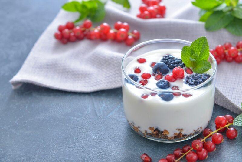 A glass filled with Activia yogurt, with currants and blueberries on top