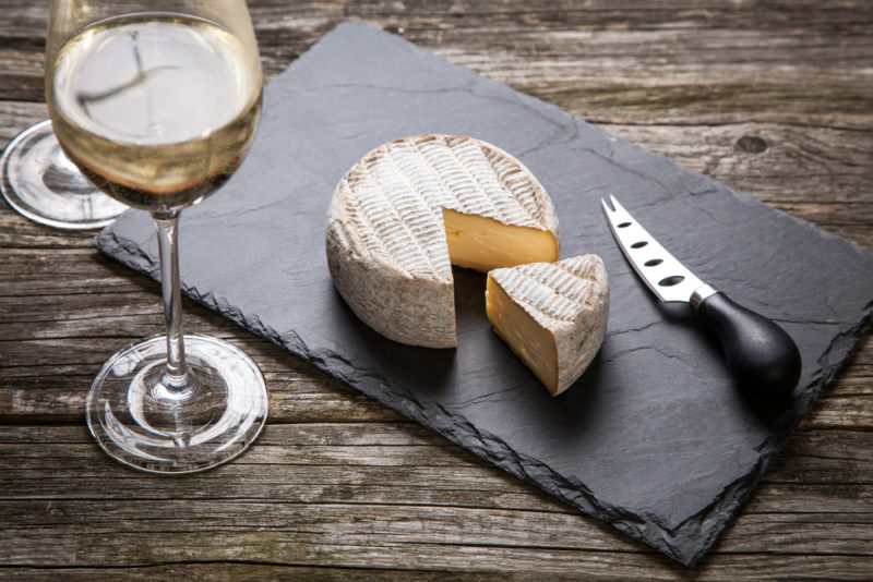 A slate slab with camembert cheese, a knife and a glass of Torrontes white wine