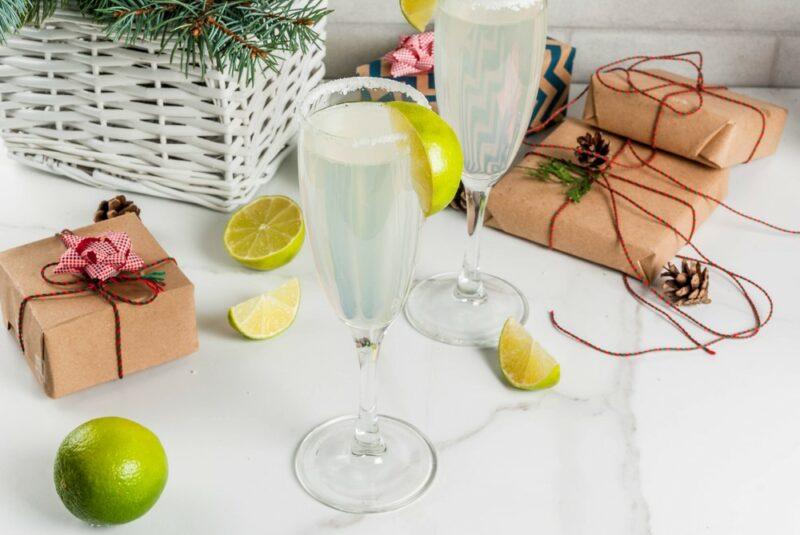 A glass of champagne margarita, with limes and presents on a table