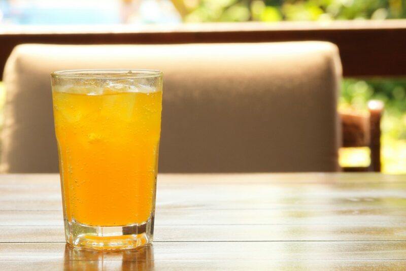 A glass of an energy Long Island iced tea cocktail on a table in front of a chair