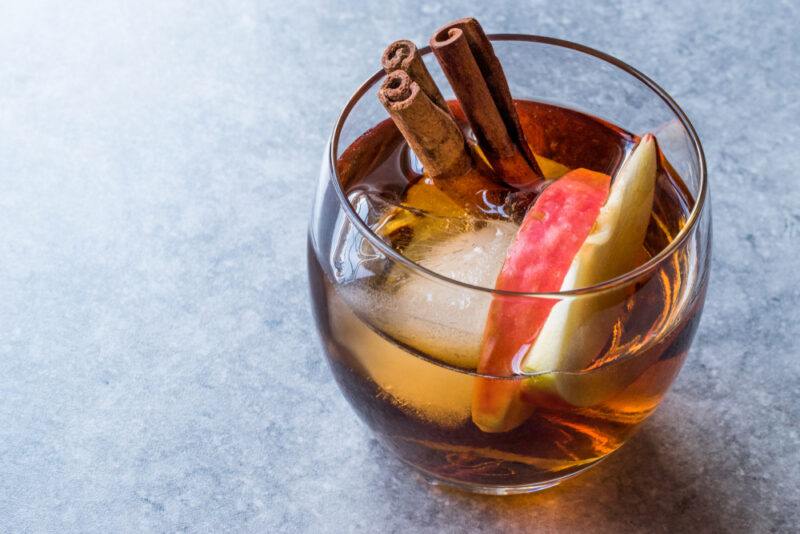 A glass of apple brandy with ice and cinnamon on a gray table