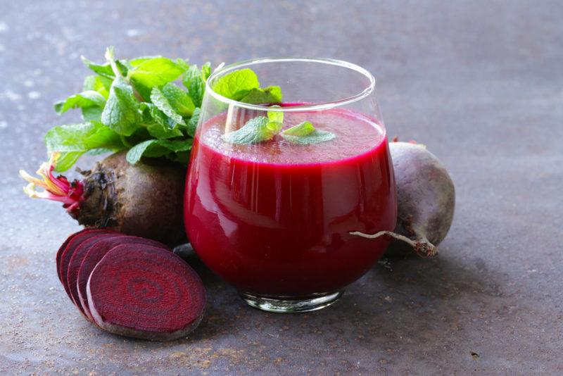 A glass of beetroot juice with whole beetroots and one that has been sliced