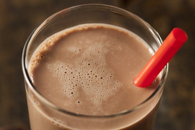 A glass of chocolate milk with a red straw