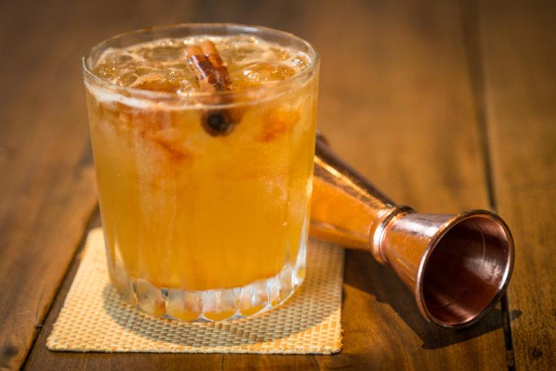 A gold rush cocktail next to a jigger on a wooden table