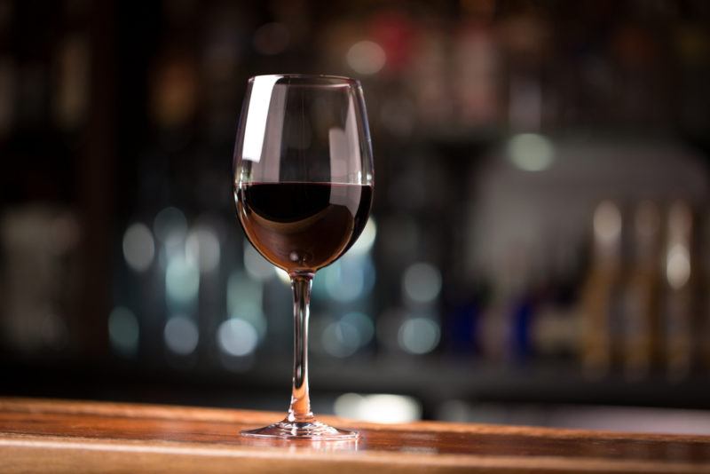 A glass of malbec on a bar with various bottles in the background