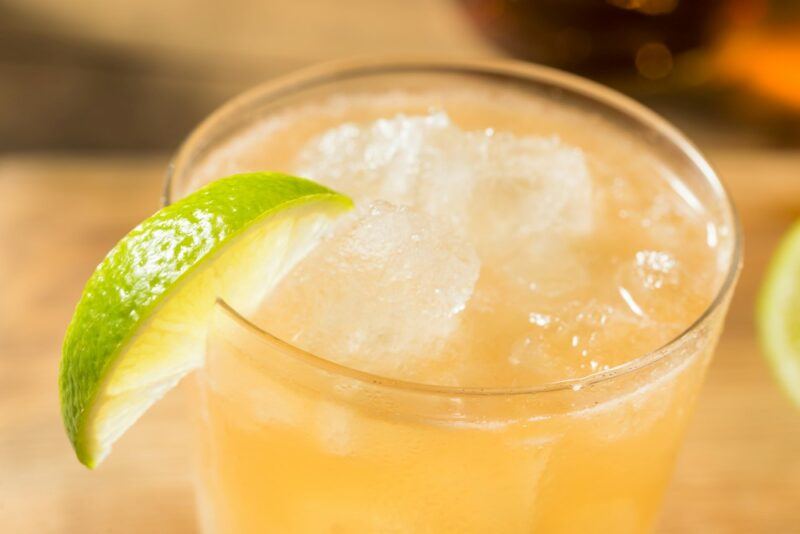 A glass containing navy grog with ice and a wedge of lime