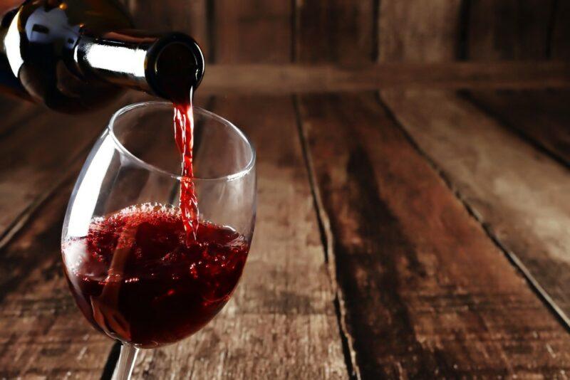 A glass of red wine being poured from a bottle