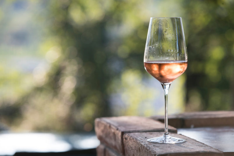 A single glass of rose wine on a table outdoors