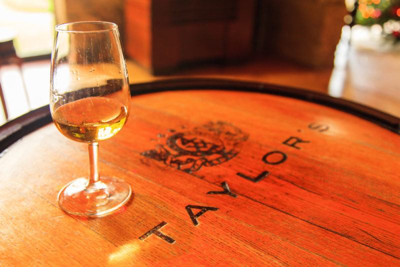 A large oak barrel with Taylor's written on top and a glass of tawny port